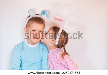 little girl kissing child boy. two happy children with Easter bunny ears on white background, copy space