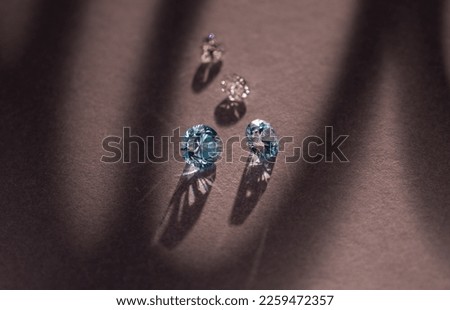 Close up of a pare of blue and white diamonds of different cuts with shadows. Royalty-Free Stock Photo #2259472357