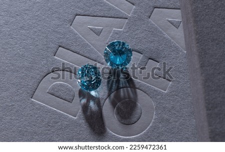 Close up of a pare of blue and white diamonds of different cuts with shadows. Royalty-Free Stock Photo #2259472361