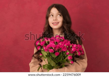 A teenage girl with a bouquet of beautiful pink roses on a pink background.