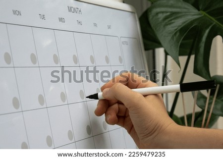 Female hand writing with marker on Monthly PLANNER. Magnetic board with the days of the month. Place to enter important matters schedule. Concept for business planning. Whiteboard Planner magnetic Royalty-Free Stock Photo #2259479235
