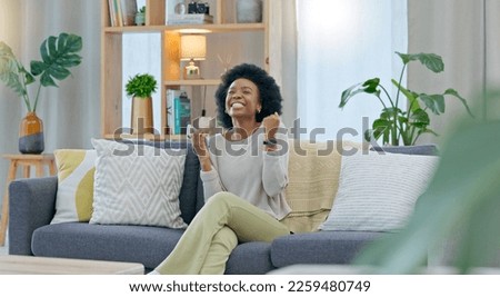 African woman celebrating a new job while sitting at home on a couch. A young females loan is approved via an email on her phone. A happy and excited lady cheering for a promotion on a sofa Royalty-Free Stock Photo #2259480749