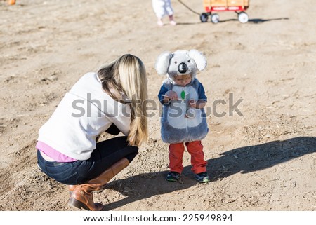 Young mother taking pictures of her kids at the pumpkin patch.