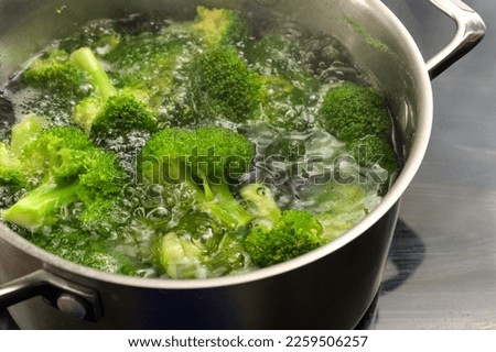Broccoli is blanched in boiling water in a stainless steel pot to preserve the fresh green color, healthy cooking with vegetables, copy space, selected focus, narrow depth of field Royalty-Free Stock Photo #2259506257