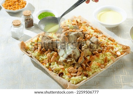 Jordanian mansaf dish with sauce (jabbaj), with fatteh yellow rice and nuts on a white background, copy space 11 Royalty-Free Stock Photo #2259506777