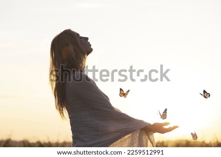 surreal encounter between a woman and free butterflies flying in the middle of nature Royalty-Free Stock Photo #2259512991