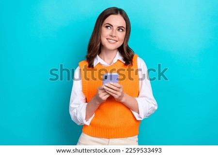Photo of positive cheerful cute woman bob hairstyle dressed orange waistcoat look empty space hold phone isolated on teal color background