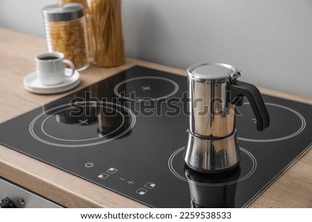 Geyser coffee maker on electric stove in kitchen near grey wall Royalty-Free Stock Photo #2259538533