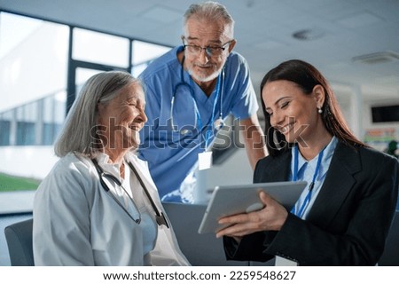 Young pharmaceutic seller explaining something to doctors in hospital. Royalty-Free Stock Photo #2259548627