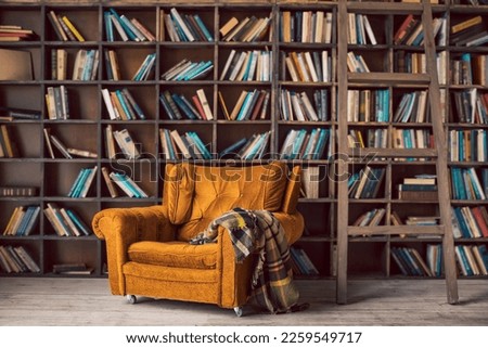 library with many shelves and books. a large orange velvet armchair with a checkered plaid. Juicy atmosphere of home cozy privacy. Horizontal composition