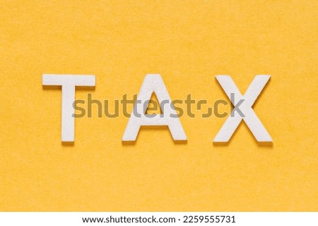 Word TAX, in white letters on yellow background, foreground