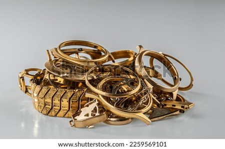 A scrap of gold. Old and broken jewelry, watches of gold and gold-plated on a grey background. Royalty-Free Stock Photo #2259569101