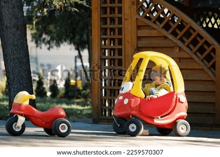 Little boy driving big toy cartoon car, outdoors.
