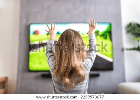 A girl listening television and watching cartoon at home. Selected focus.