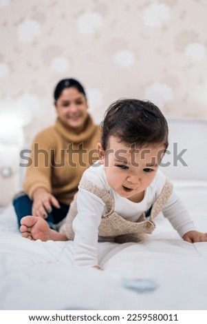 Stock photo of beautiful baby playing with her mom in the bed.