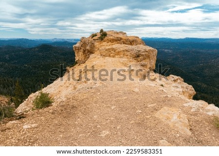 Hiking Strawberry Point Ridge in the Dixie National Forest, Utah. Walking the rim of a breathtaking red-rock ridge. A beautiful view of vast valleys filled with pine trees and distant blue mountains Royalty-Free Stock Photo #2259583351
