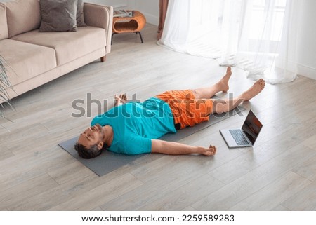 Photo of a man on the floor, relaxation and mental health. Relaxation practice with online tutorial. Yoga - shavasana. Royalty-Free Stock Photo #2259589283