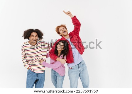 Young beautiful stylish international funny friends posing and fooling over isolated white background . Two men and woman