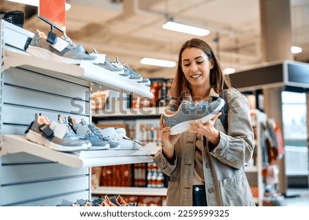 Young happy woman buying sports shoes at shopping mall.  Royalty-Free Stock Photo #2259599325