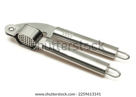 Metallic shiny garlic press crusher tool isolated on white background. Stainless kitchen utensil mincer Royalty-Free Stock Photo #2259613141