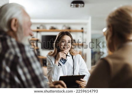 Happy female nurse talking with her patients  during a home visit