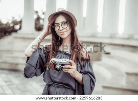 Pretty woman tourist with a camera in the city. Travel concept