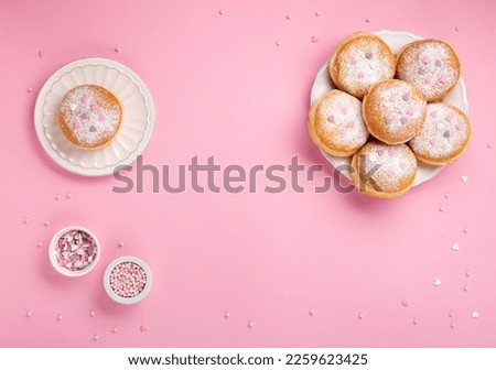 Happy National donut day or Valentines Day Concept. Donuts doughnuts with icing sugar and sugar sprinkles on pink background, copy space. Colorful carnival or birthday party card. Royalty-Free Stock Photo #2259623425