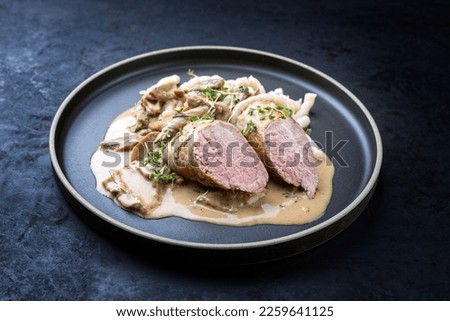 Modern style traditional barbecue Iberian pork filet medaillons in cream sauce with mushrooms and herbs offered as close-up on a Nordic design plate with copy space  Royalty-Free Stock Photo #2259641125
