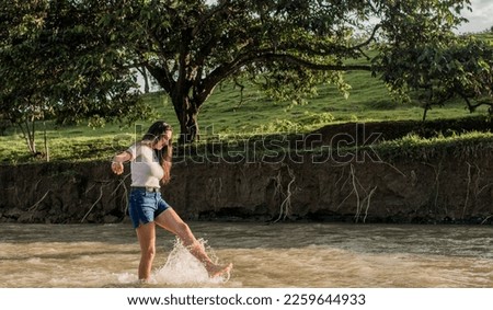 young woman playing with water in the river in summertime 