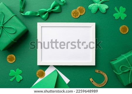 Saint Patrick's Day concept. Top view photo of empty white photo frame gift boxes gold coins bow-tie horseshoe envelope with postcard and clovers on isolated green background with copyspace