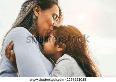 Happy latin mother and daughter having tender moment together outdoor - Focus on mom eye