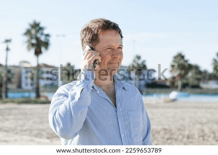 Businessman Talking On Phone, using smartphone mobile apps texting message, surfing social media tech standing in urban city on modern street outdoors.
