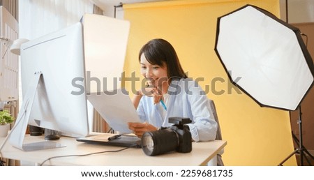 asian female photographer is using color graphic chips to check up colour of pictures in digital camera through computer and she satisfied with the work