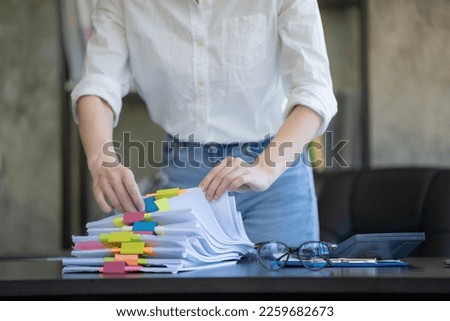 Businesswoman hands working in Stacks of paper files for searching and checking unfinished documents achieves on folders papers at busy work desk office.