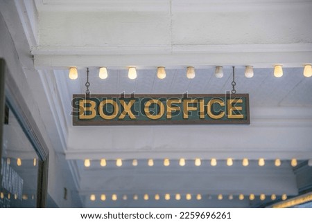 Box Office on a wooden signage hanging on a ceiling with small light bulbs in a row at Austin, TX. Signage hanging below the white ceiling.