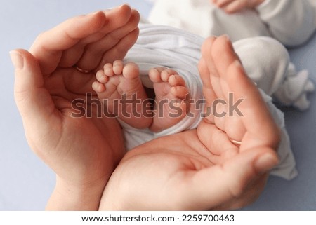 Small feet of a newborn in the hands of parents. Loving palms of the hands of mother. Conceptual image of fatherhood. Close-up, selective focus. Professional photography a white background.