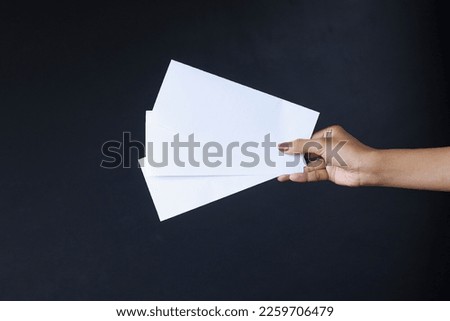 Woman hand holding three  blank flyer on a dark gray background. Flyer Mock-Up.