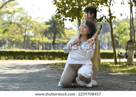 Image of happy mature woman and her cute grandchild enjoying leisure weekend time together outdoor