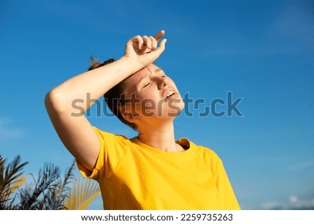 Girl is suffering from heat, woman with heatstroke. Having sunstroke at summer hot weather. Dangerous sun, girl under sunshine. Headache. Person holds hand on head. Feeling bad, unwell, unhealthy Royalty-Free Stock Photo #2259735263