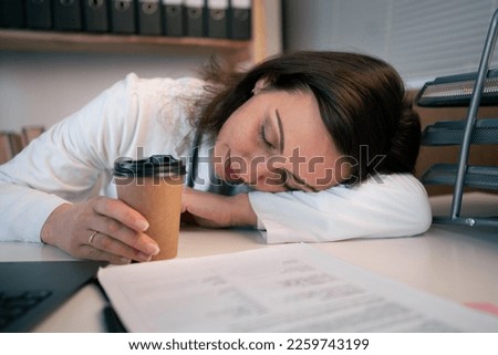 Overworked female doctor sleeping on desk with glass of coffee in medical office, close up. Medical and healthcare concept