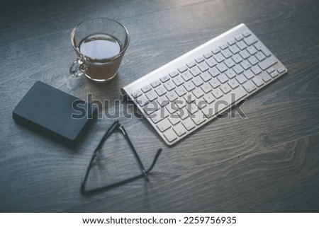 Desktop view with keyboard pencil agenda and technology devices. Table with objects for smart working homeschooling and cup of coffee. Organization, remote work, study, creativity, production concept.