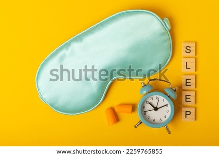 Sleep mask and alarm clock on a yellow background. Sweet dreams concept. The concept of rest, sleep quality, good night, insomnia and relaxation. Flat lay, mockup. view from above