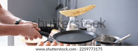 Person deftly flips the pancakes in pan Royalty-Free Stock Photo #2259773175