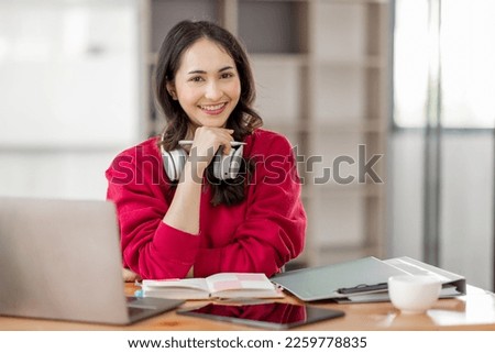 Portrait of Young asian woman wearing headphones using laptop in cafe, writing notes, learning language, watching online business or education concept