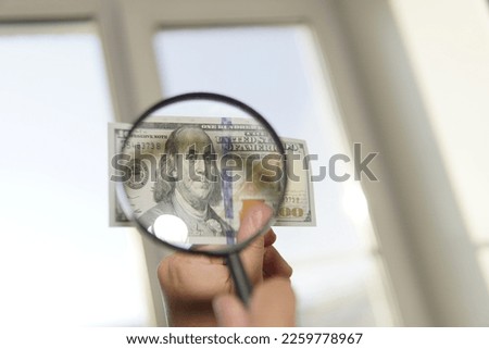 Counterfeiter forges banknotes. Fake concept. Fake money American dollars, magnifier. view money under a magnifying glass. watermark, water mark