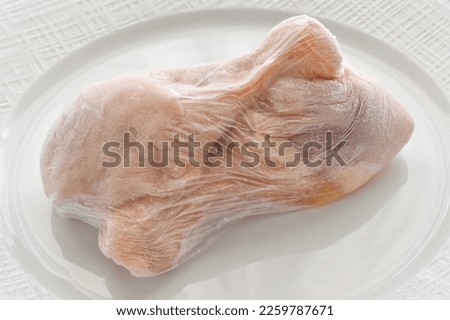 Frozen chicken legs in food plastic wrap.  Photo can be used for how to wrap meat for freezer concept.  Royalty-Free Stock Photo #2259787671