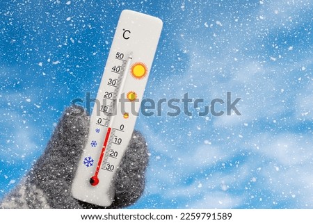White celsius scale thermometer in hand. Ambient temperature zero degrees celsius