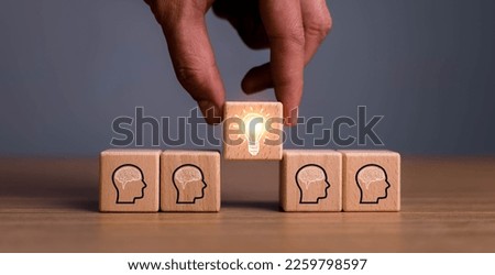 brainstorming creative idea and innovation. Hand putting over wooden cube block with light bulb icon on many people together having an idea symbolized by icons on cubes. Royalty-Free Stock Photo #2259798597