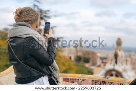 Tourist woman taking photo with smartphone in Park Guell, Barcelona, Spain. Smartphone sightseeing photography in Spain, Europe.