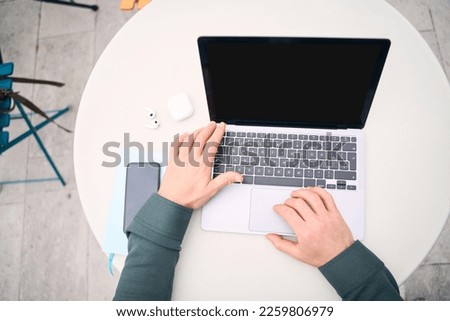 Top view of freelancer hands using laptop computer working online, looking at black screen sitting at workplace, selective focus. Mockup